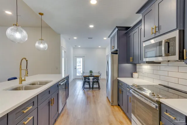 a kitchen with stainless steel appliances granite countertop a sink a stove and a wooden floors