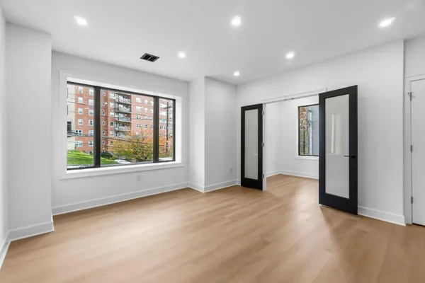 an empty room with wooden floor and windows