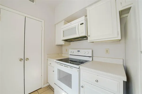 a kitchen with white cabinets and white appliances