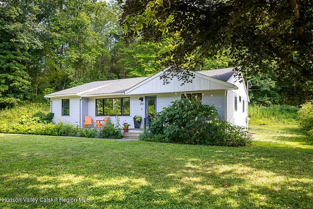 a front view of a house with a yard and green space