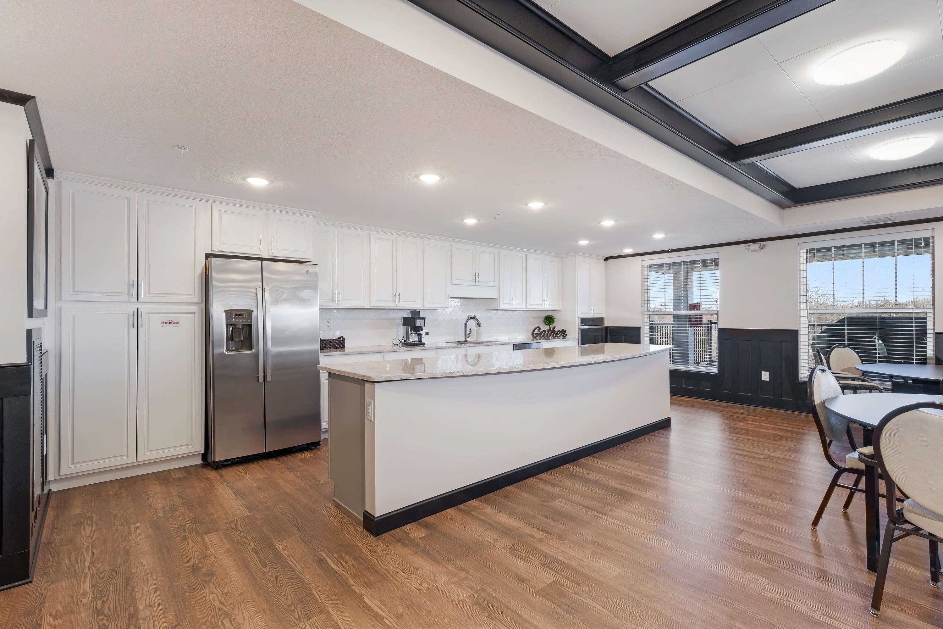 2592 Middle Road, Unit 208 Bettendorf, IA 52722 - Photo 17 of 19 a large white kitchen with stainless steel appliances kitchen island a stove a refrigerator a oven a dining table and chairs with wooden floor