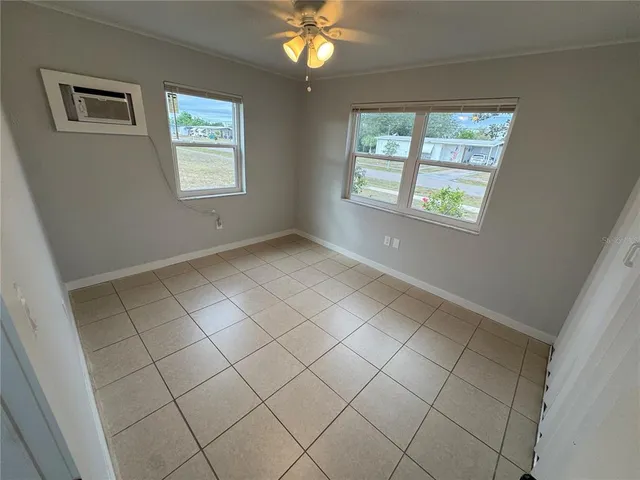 a view of an empty room with window and chandelier fan