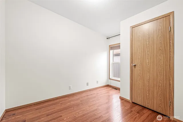 an empty room with wooden floor chandelier fan and windows