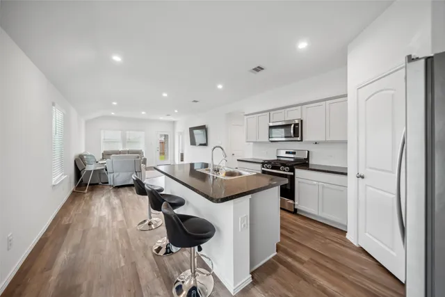 a kitchen with stainless steel appliances kitchen island granite countertop a stove and a refrigerator
