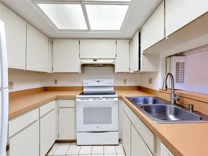 a kitchen with white cabinets sink and appliances