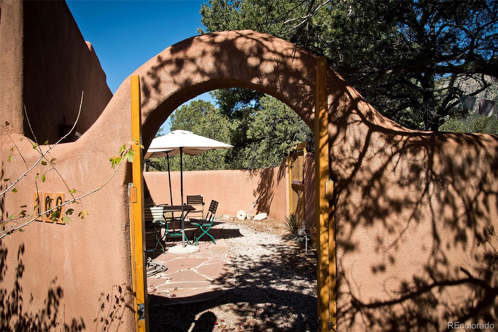 109 Pinewood Overlook Crestone, CO 81131 - Photo 26 of 35 a backyard of a house with table and chairs under an umbrella