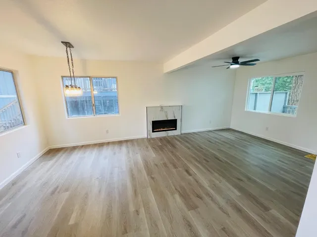 an empty room with wooden floor windows and cabinet