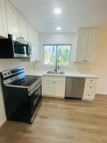a kitchen with stainless steel appliances a stove a sink and white cabinets