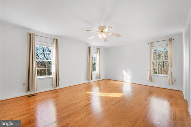 a view of empty room with wooden floor and fan
