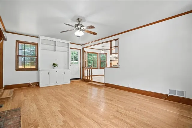 a view of an empty room with window and wooden floor