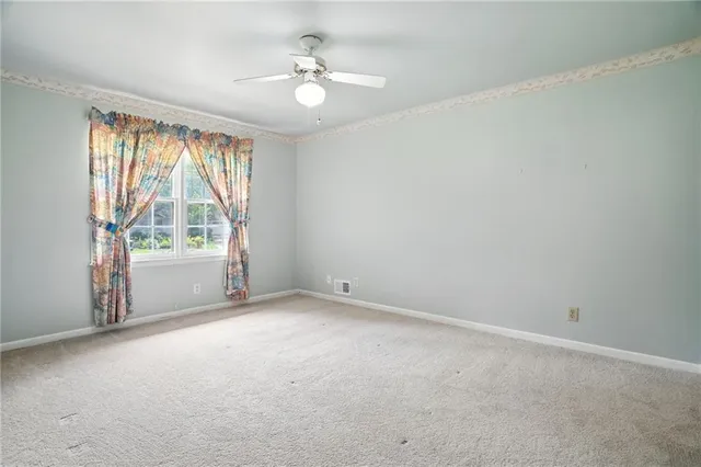 an empty room with a ceiling fan and a window