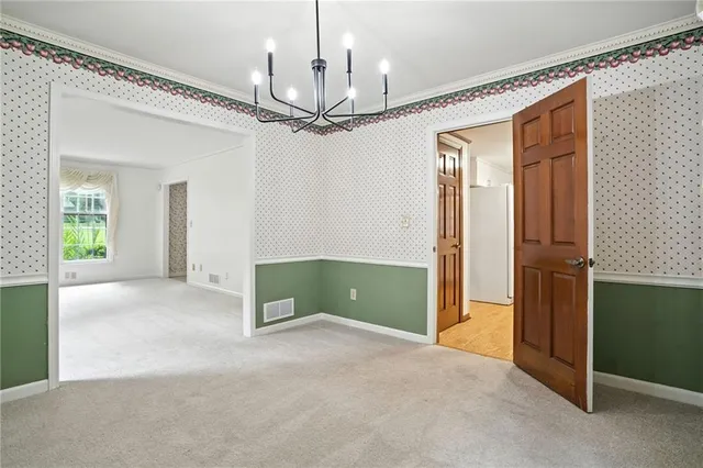 a view of an empty room with a window and a kitchen