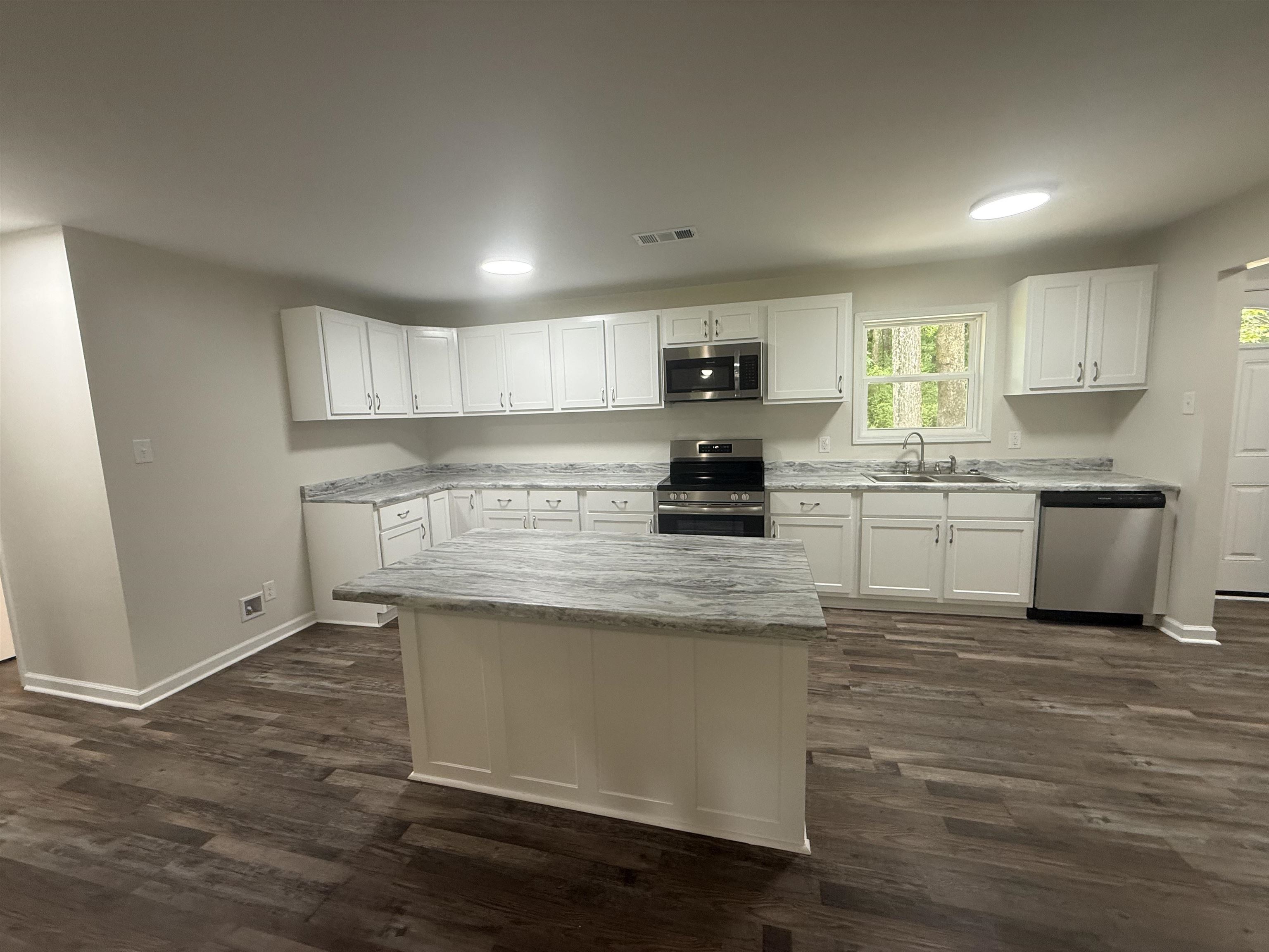 195 Poole Road Moscow, TN 38057 - Photo 7 of 21 Modern kitchen featuring white cabinetry, a central island with a stone-look countertop, stainless steel appliances, wood-finish flooring, and recessed lighting
