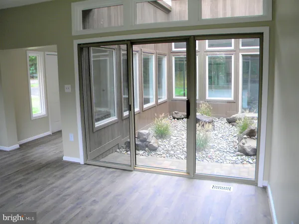a view of a room that has a large window and wooden floor
