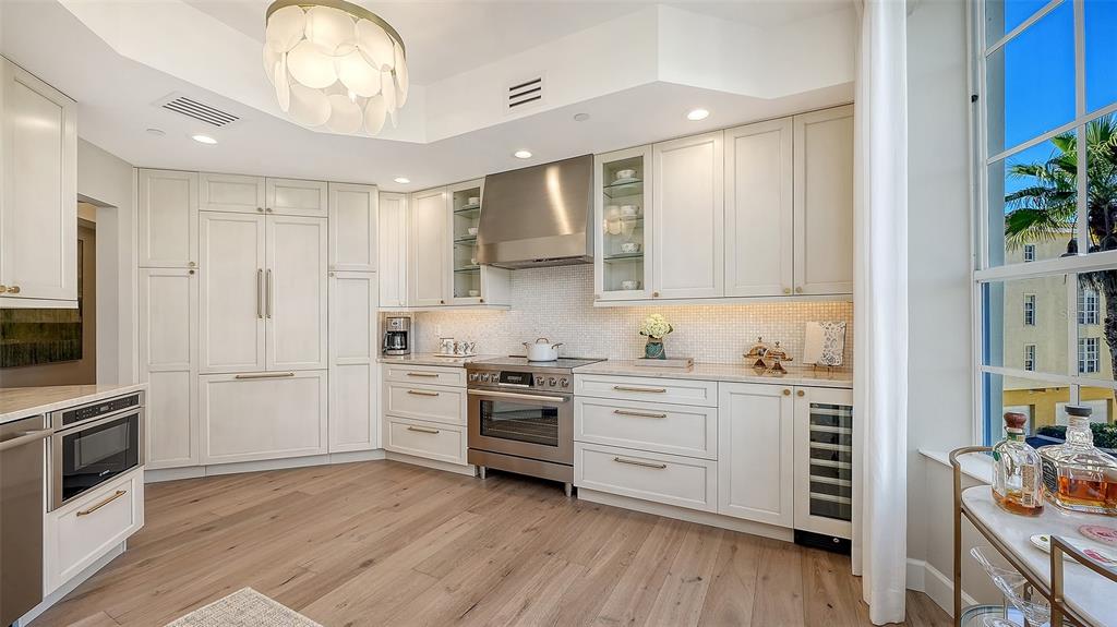 6465 Water Crest Way, Unit 301 Lakewood Ranch, FL 34202 - Photo 17 of 85 a kitchen with white cabinets stainless steel appliances and wooden floor