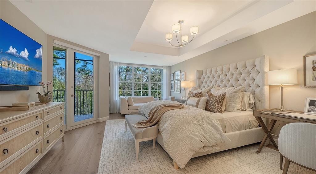 6465 Water Crest Way, Unit 301 Lakewood Ranch, FL 34202 - Photo 28 of 85 a bedroom with a large bed and a chandelier