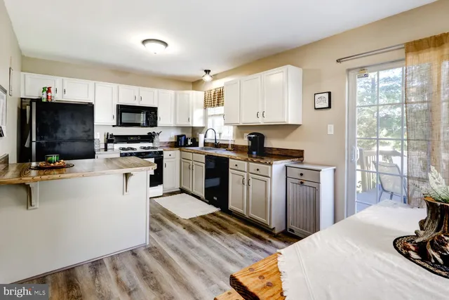 a kitchen with stainless steel appliances granite countertop a refrigerator a stove a sink dishwasher and white cabinets with wooden floor