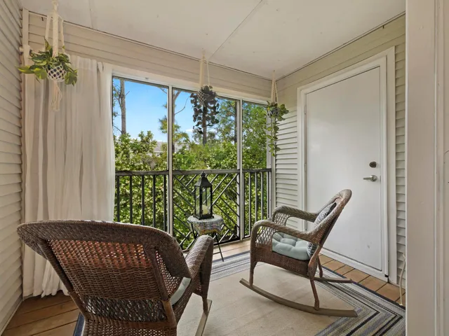 a living room with large windows and a potted plant