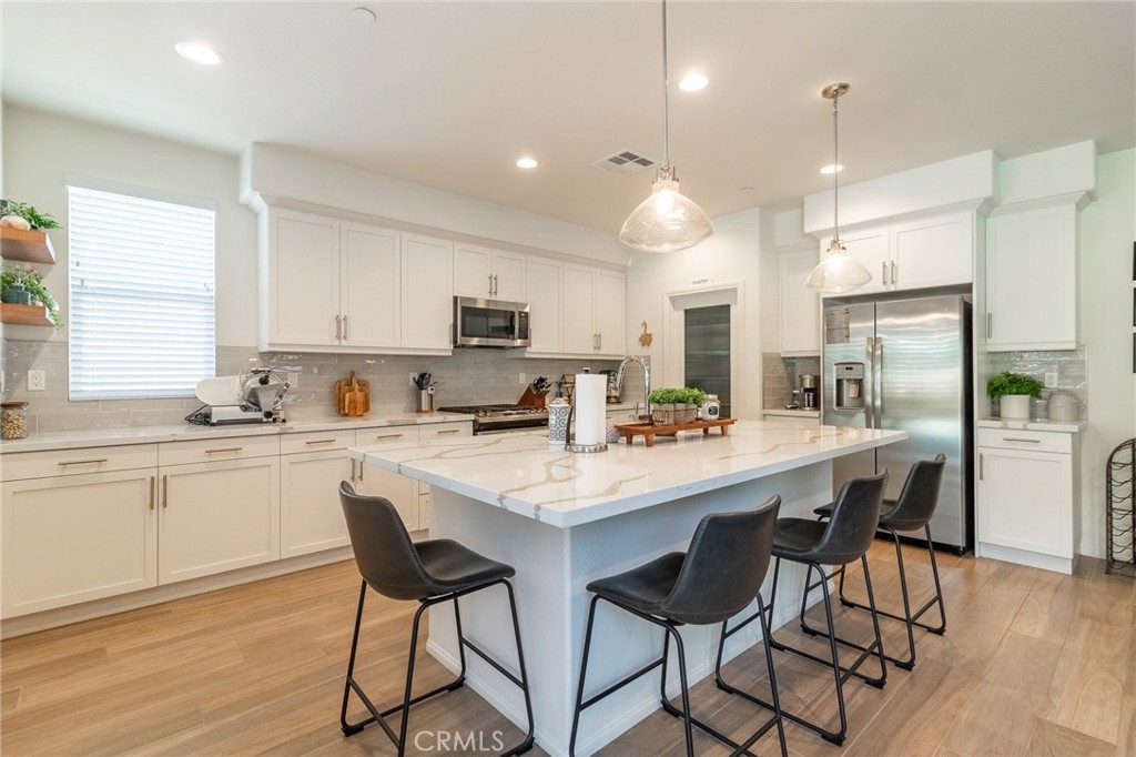 1827 Montecito Lane Redlands, CA 92374 - Photo 15 of 60 a kitchen with stainless steel appliances kitchen island granite countertop a table chairs sink and cabinets