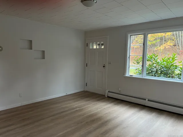 a view of an empty room with wooden floor and a window