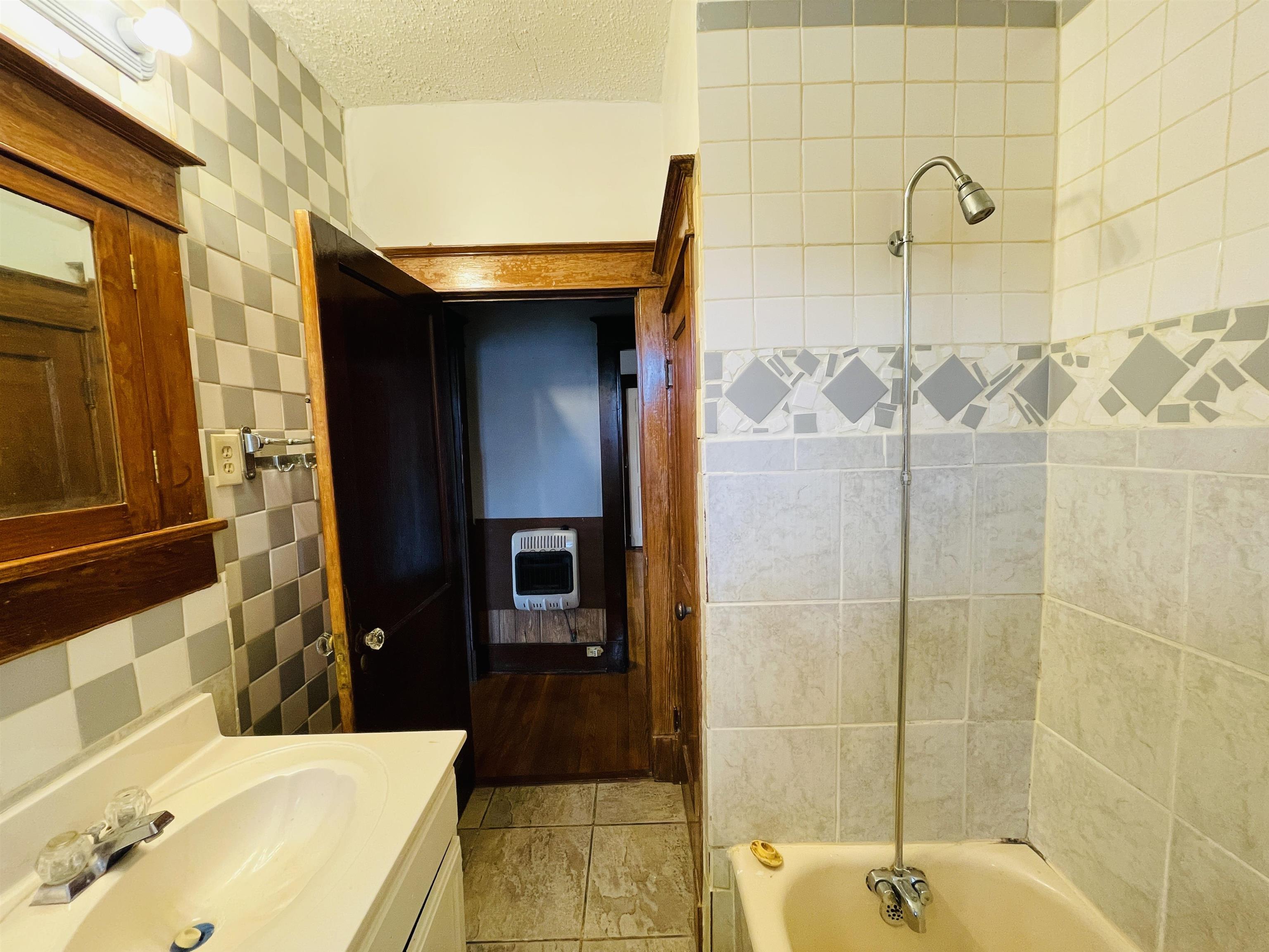 1009 Rozelle Street Memphis, TN 38114 - Photo 37 of 40 Bathroom with vanity, a textured ceiling, heating unit, and tile walls