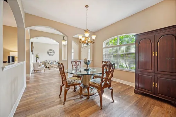 a dining room with furniture a chandelier and wooden floor