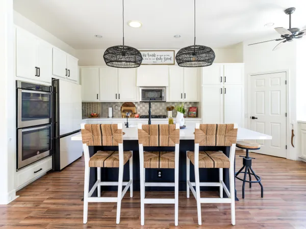 a kitchen with stainless steel appliances kitchen island granite countertop a dining table chairs and a refrigerator