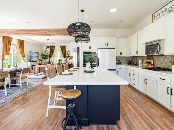 a kitchen with stainless steel appliances a dining table chairs and white cabinets