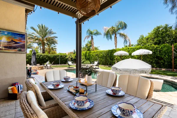 a view of a patio with table and chairs potted plants and palm tree