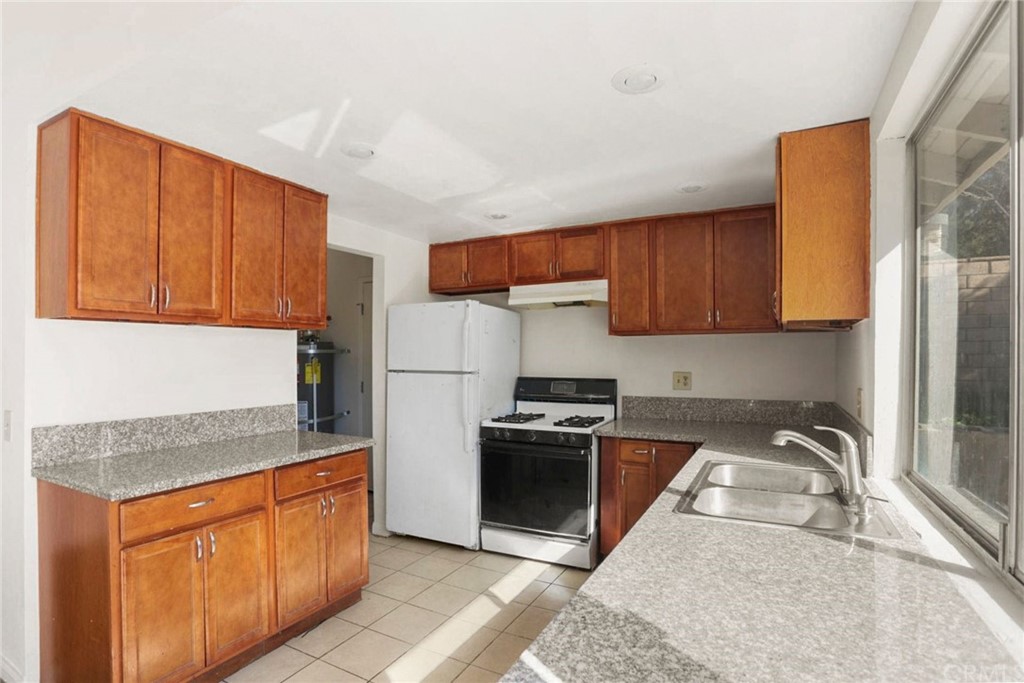 340 Maravilla Drive Riverside, CA 92507 - Photo 13 of 35 a kitchen with stainless steel appliances granite countertop a stove a sink dishwasher and a refrigerator with wooden cabinets