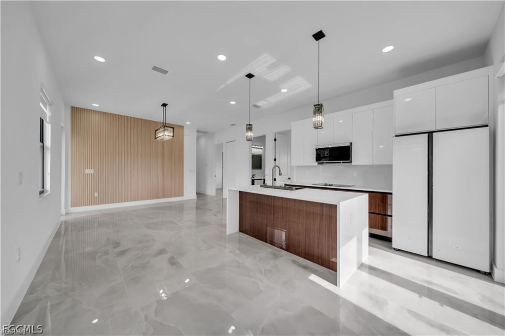 711 Roma Avenue South Lehigh Acres, FL 33974 - Photo 8 of 38 a large kitchen with stainless steel appliances kitchen island a large counter top and a sink
