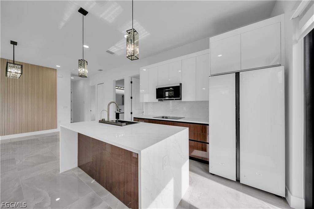 711 Roma Avenue South Lehigh Acres, FL 33974 - Photo 9 of 38 a kitchen with kitchen island a sink stainless steel appliances and chandelier
