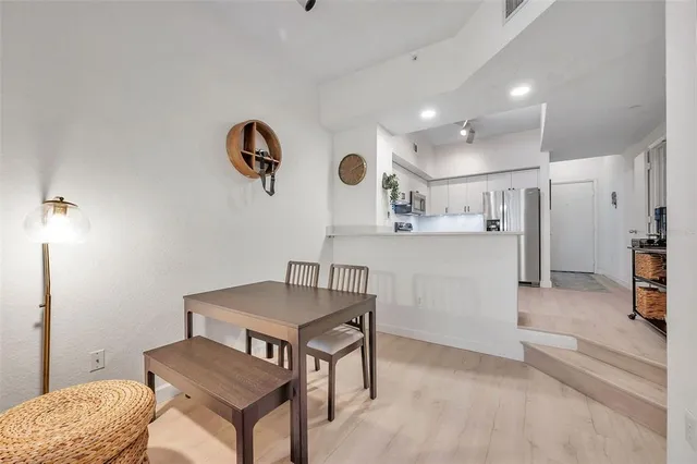 a kitchen with stainless steel appliances granite countertop a stove top oven a sink a dining table and chairs with wooden floor