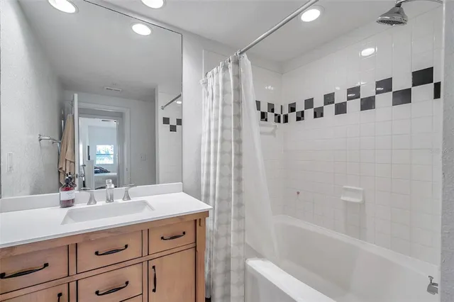 a bathroom with a double vanity sink a mirror a bathtub and shower
