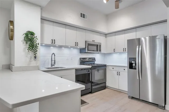 a kitchen with stainless steel appliances granite countertop a refrigerator sink and stove