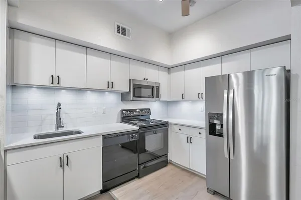 a kitchen with stainless steel appliances granite countertop a refrigerator sink and white cabinets