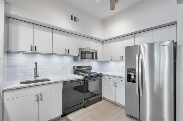 a kitchen with stainless steel appliances granite countertop a refrigerator sink and white cabinets