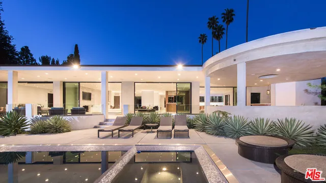 a view of a patio with couches table and chairs with potted plants and wooden fence