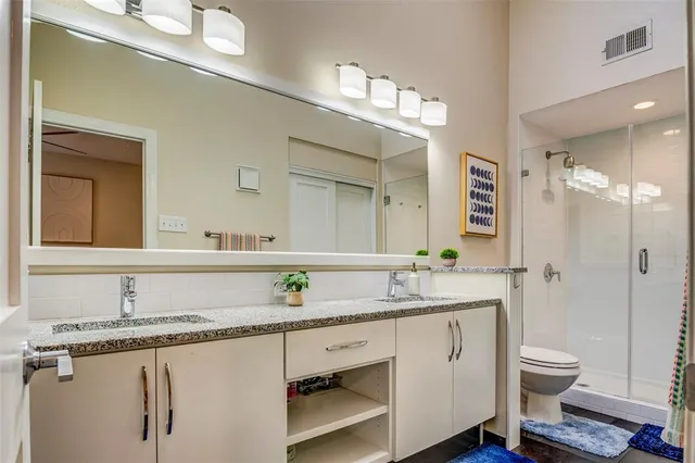 a bathroom with a granite countertop sink a toilet a mirror and shower