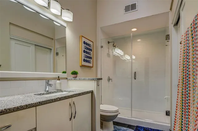 a bathroom with a granite countertop sink a toilet and shower