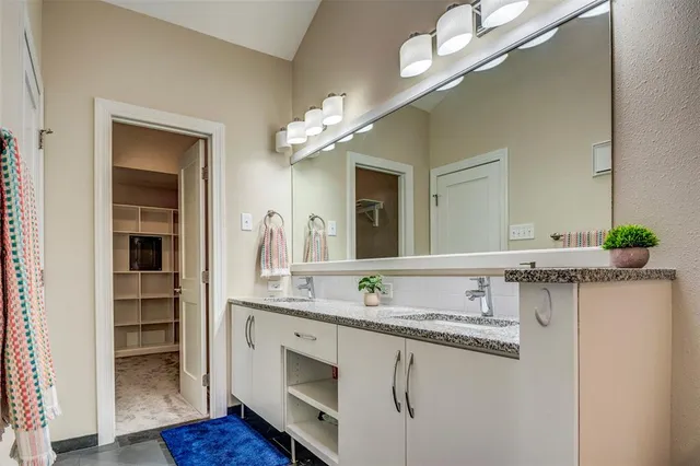 a bathroom with a granite countertop sink a large mirror and a wooden floor
