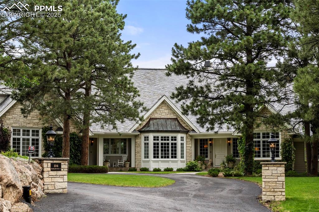 a view of a white house next to a yard with big trees