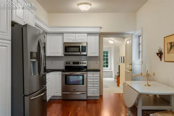 a kitchen with a sink stainless steel appliances and wooden floor