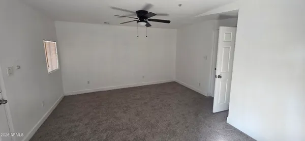 an empty room with a window and a fan