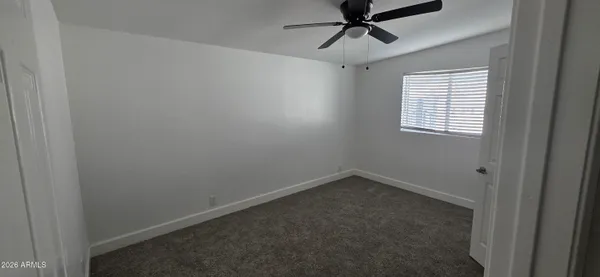 an empty room with a window and a fan
