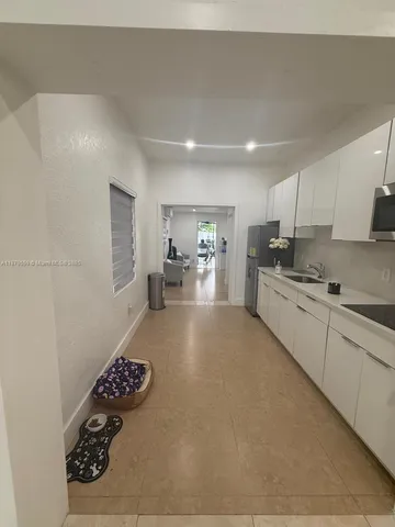 a kitchen with a refrigerator and white cabinets