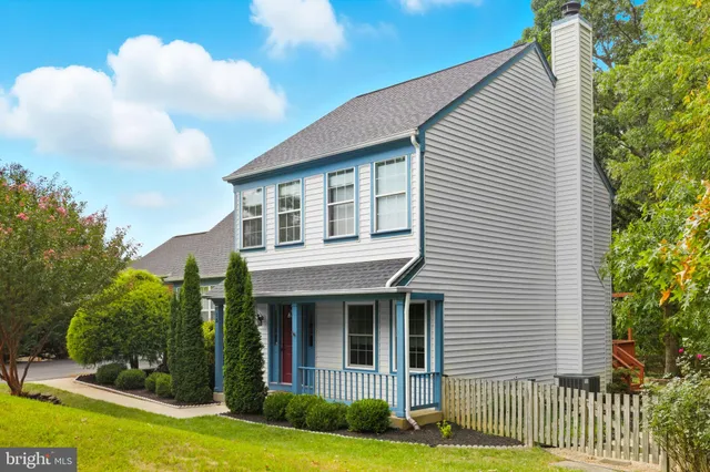 a view of a white house next to a yard with plants and trees