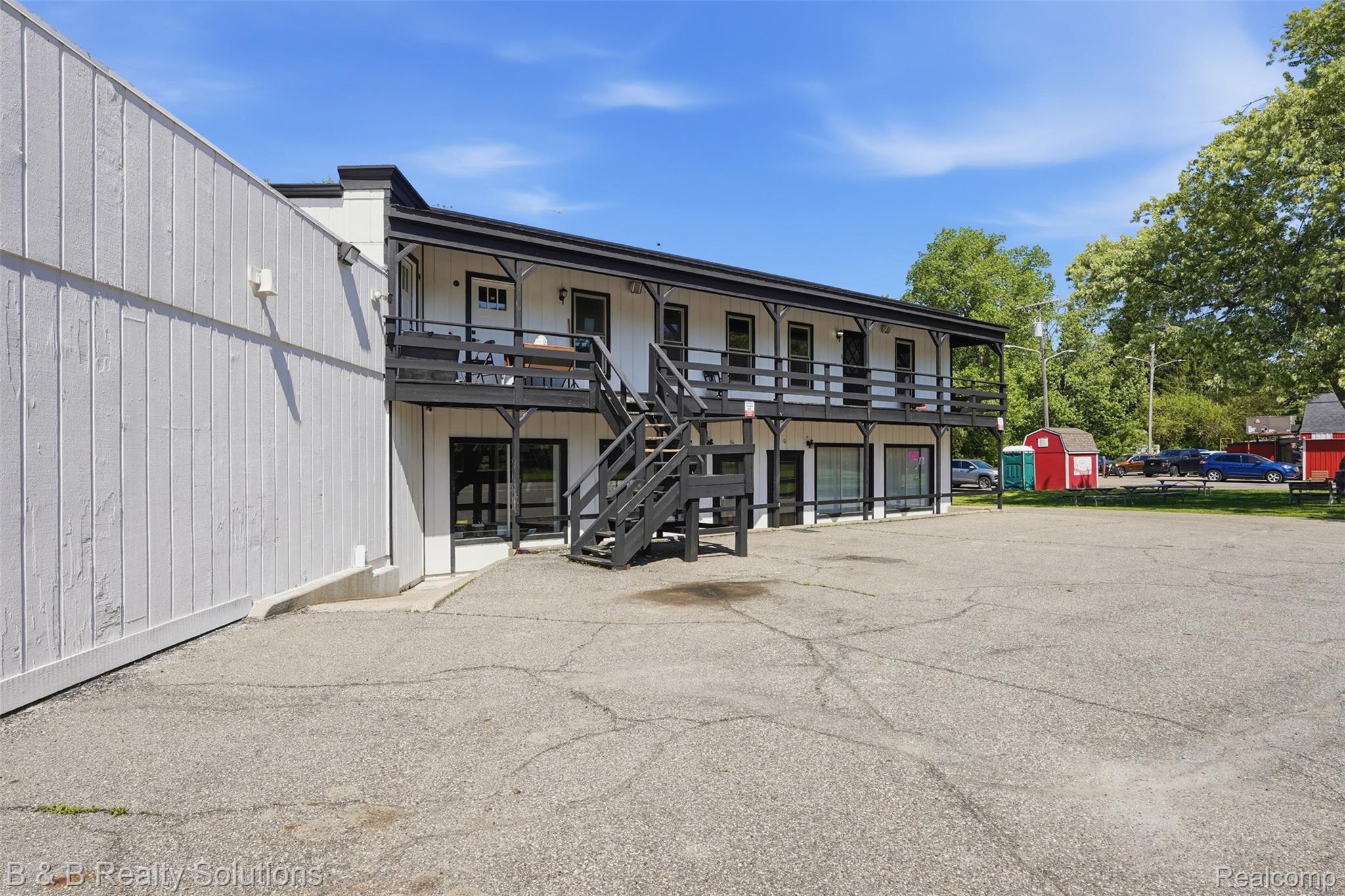 780 North Van Dyke Road, Unit APARTMENT #1 Almont, MI 48003 - Photo 2 of 28 Two-story building with white siding and black trim, featuring an exterior staircase and upper-level balcony