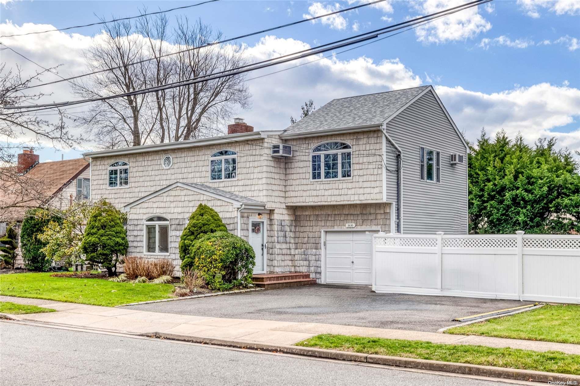 2630 Riverside Avenue Merrick, NY 11566 - Photo 1 of 1 a front view of a house with a garden and garage