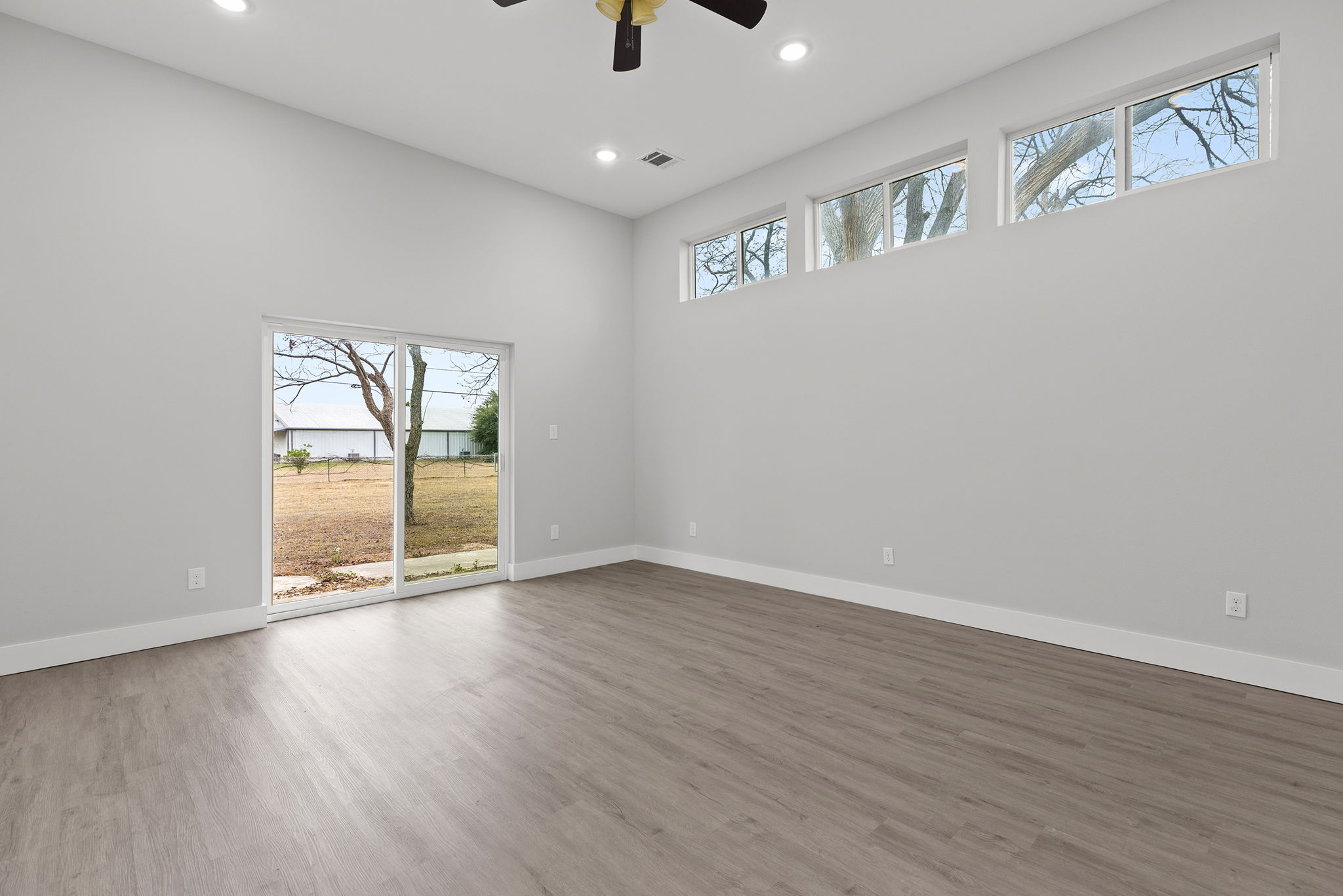 813 Central Avenue Elgin, TX 78621 - Photo 19 of 22 Spare room with plenty of natural light, light wood-type flooring, a ceiling fan, recessed lighting, and a high ceiling